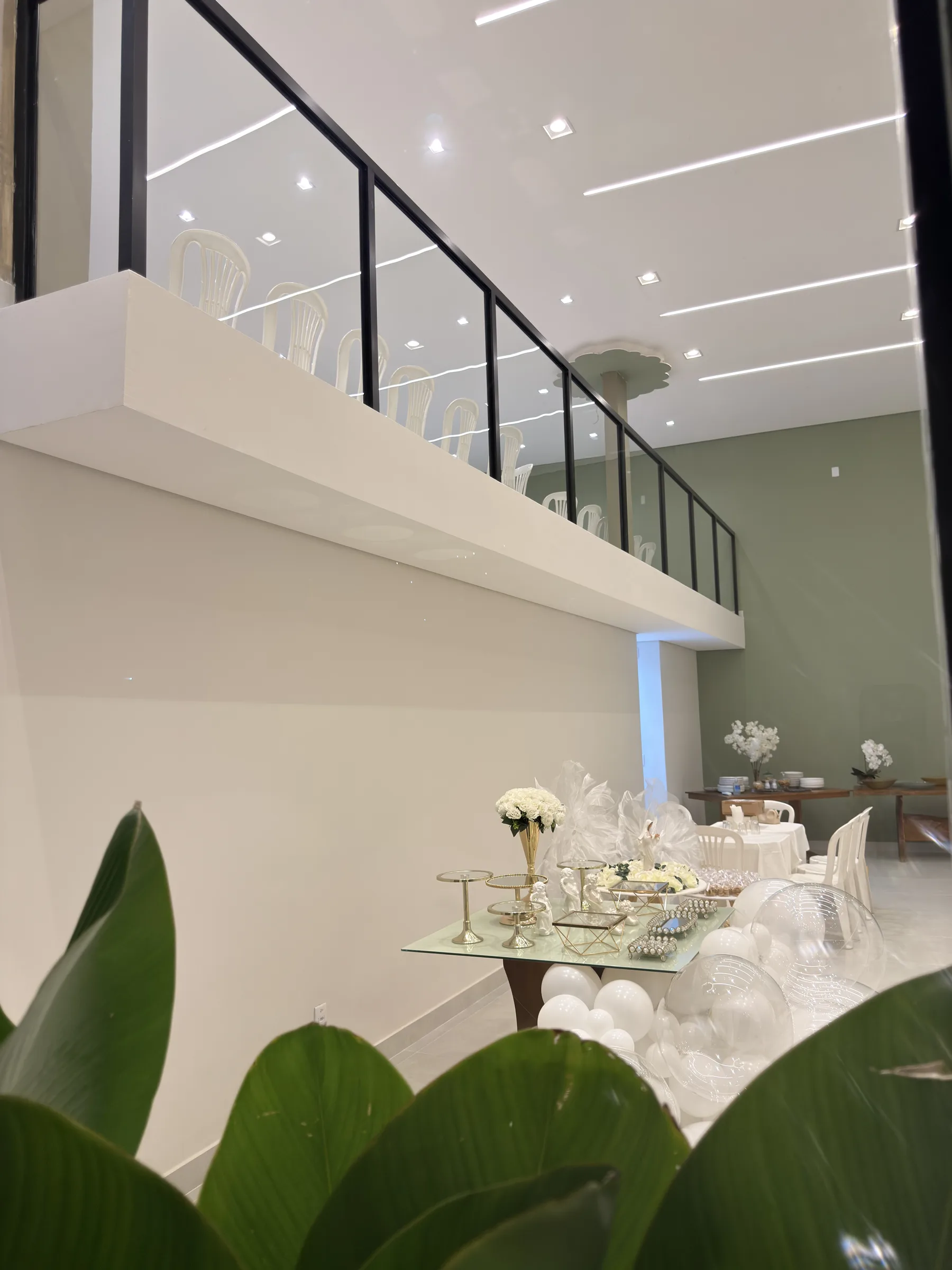 Salão principal da Dondoka com parede verde oliva, mesas montadas e mezanino ao fundo