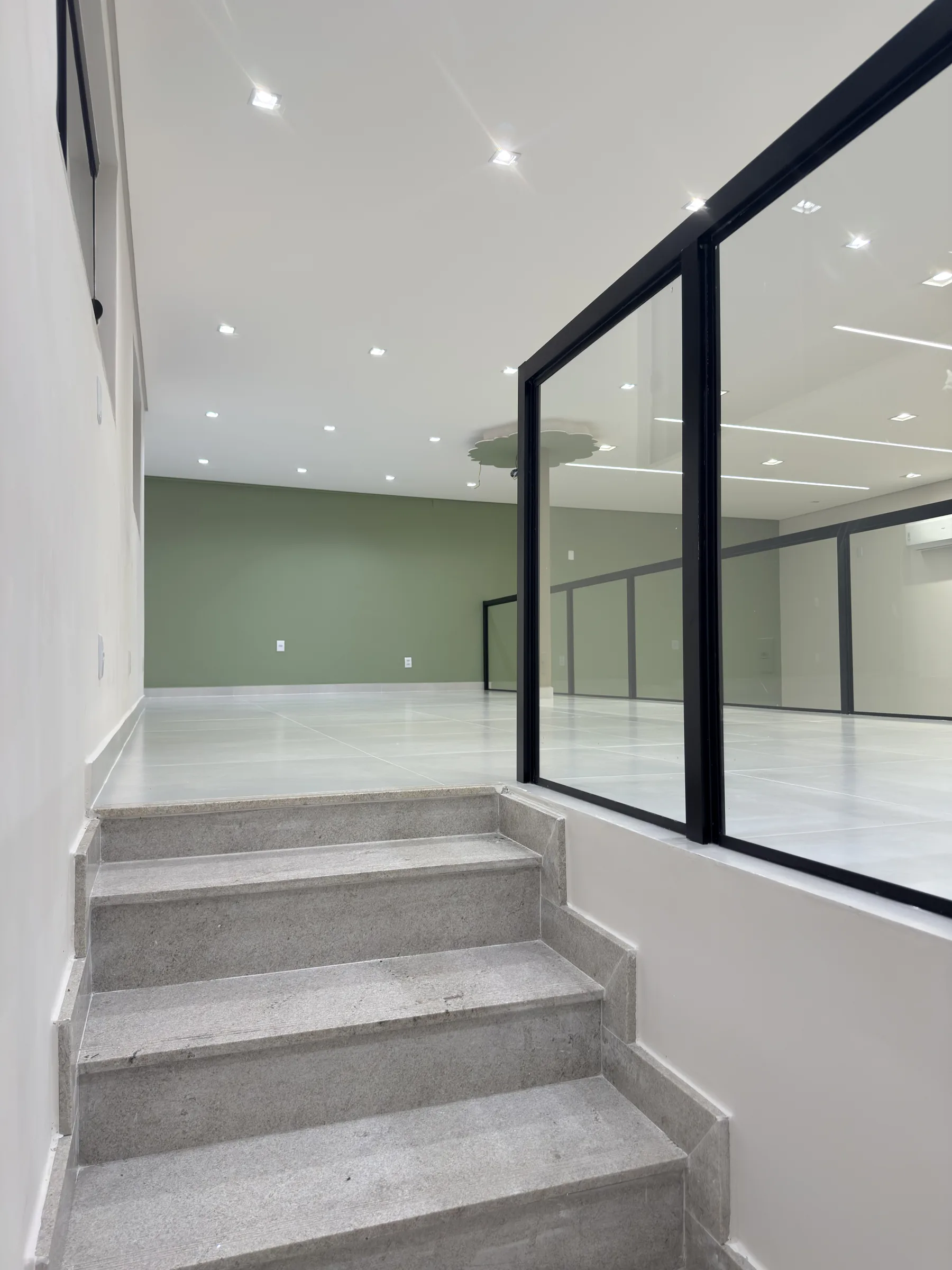 Escada e guarda-corpo de vidro que ligam os dois ambientes da Dondoka Recepções